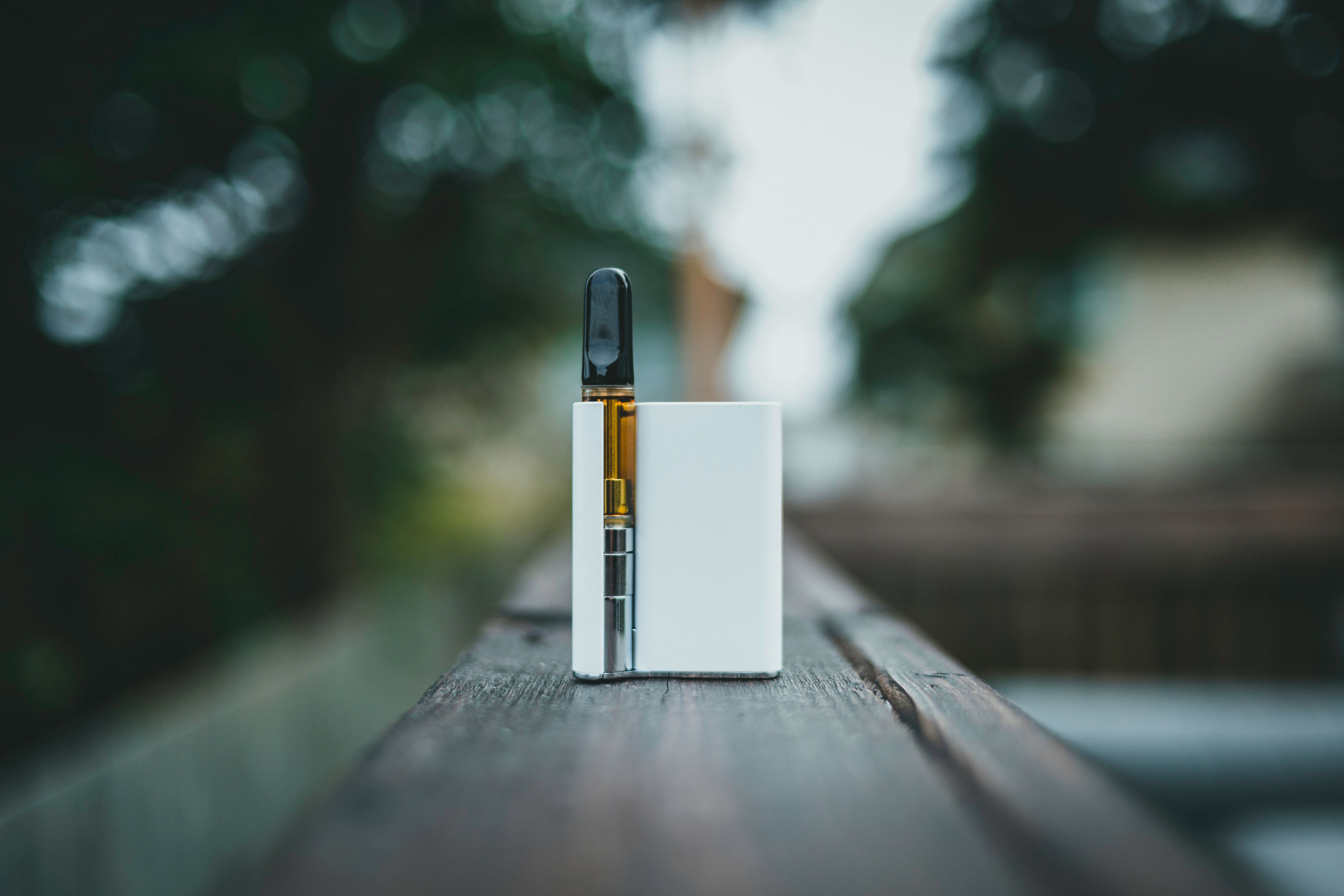 A sleek vape hardware device resting on a wooden surface outdoors