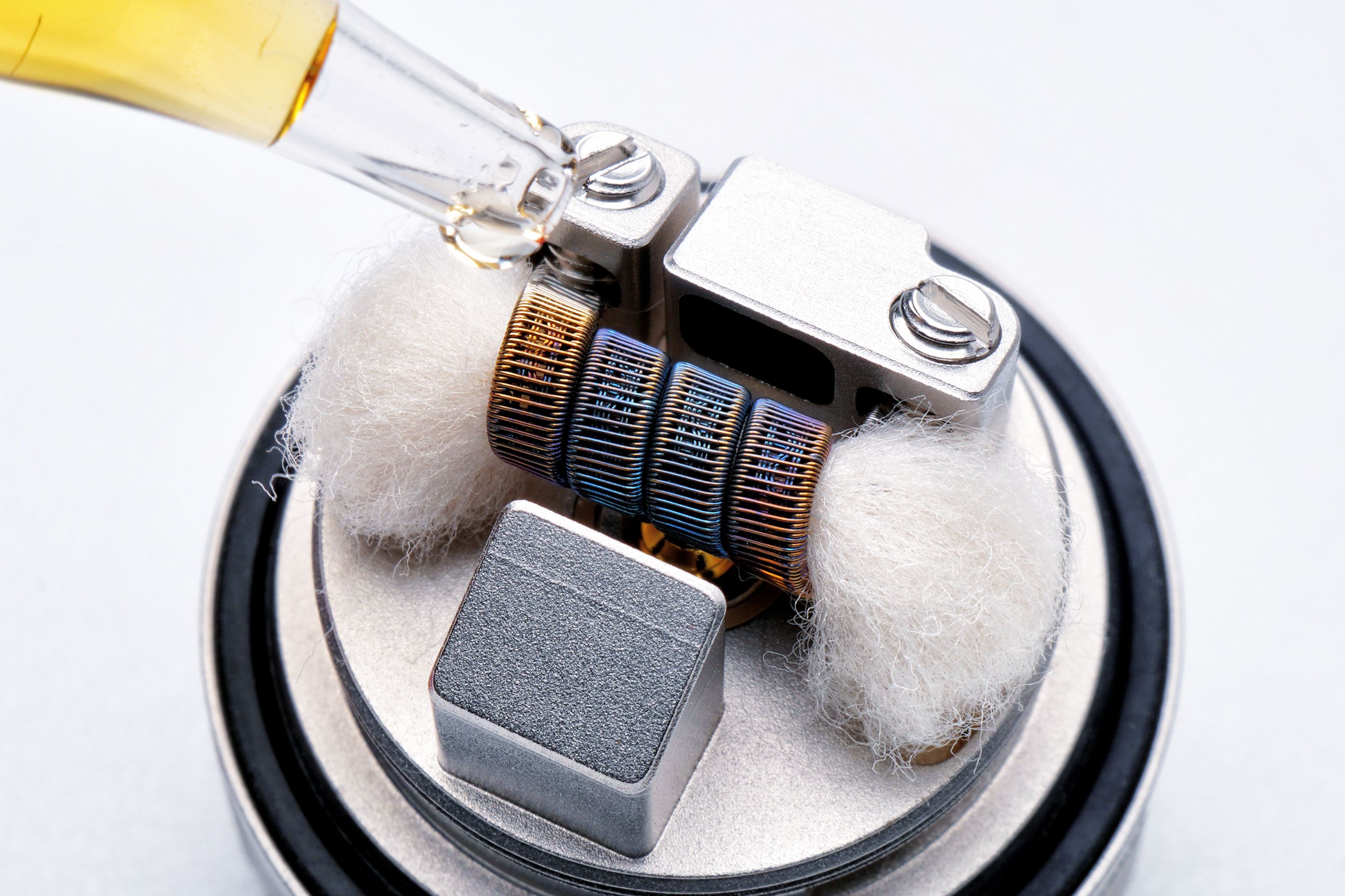 Macro shot of a vape heating coil being primed, showing craftsmanship